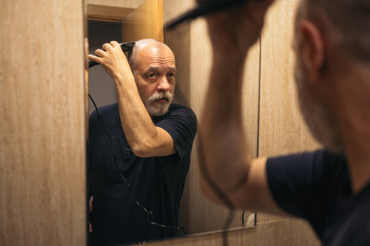 A man shaving his head in the bathroom