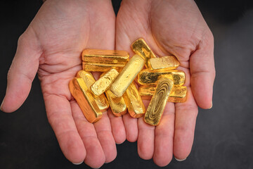 Hands holding solid gold bars