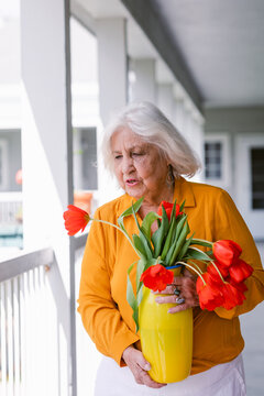 80s woman holding yellow vase with red tulips at residence 