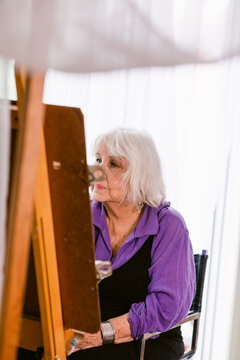 Artist elder woman painting at home
