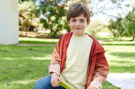 Smiling little boy kneeling outside in a park