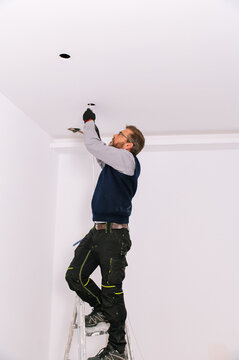 Male electrician installing ceiling illumination