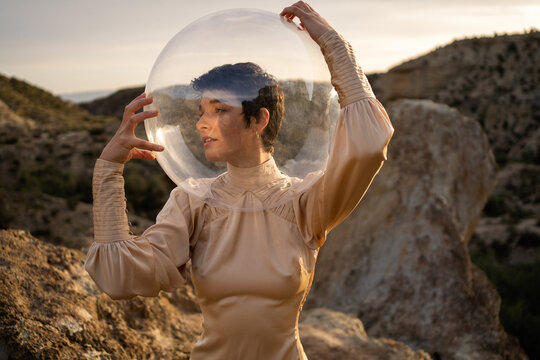 Portrait Of A Woman With Dress And Transparent Helmet In The Desert.