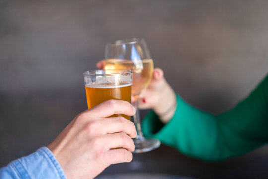 Faceless couple toasting with beer and wine during date