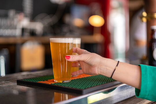 Crop woman taking beer pint from bar counter