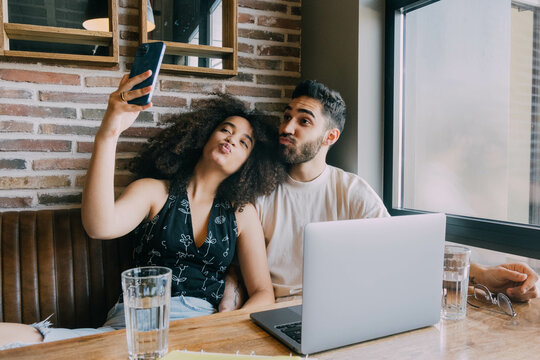 Cheerful Young Couple Taking selfie In Cafe
