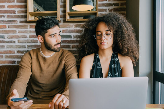 Couple Sitting In Cafe And Using Laptop