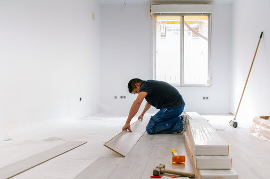 Hispanic man installing floor in new apartment