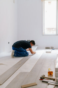 Hispanic man installing floor in new apartment