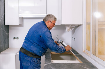 worker installing sink in kitchen