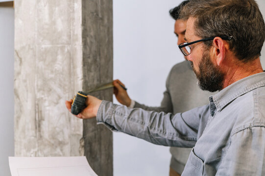 Men with draft examining apartment wall