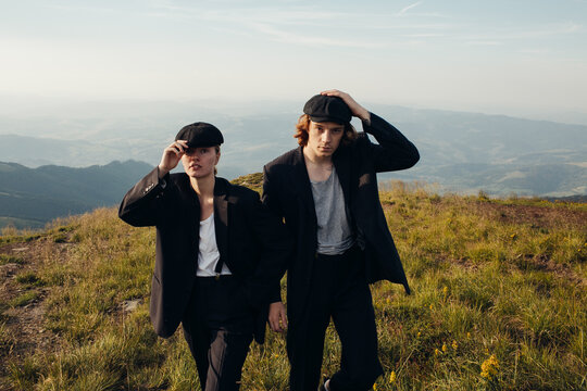 Beautiful couple in black suits and caps in the mountains