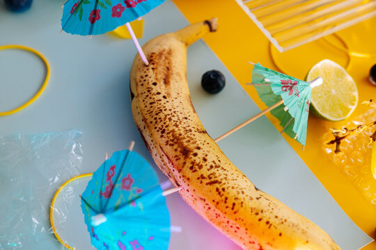 Still life with ripe banana and paper umbrella for a cocktail.
