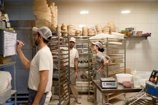 Cheerful aker colleagues working in professional bakery