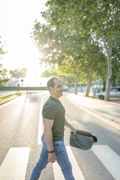 young man walking across a zebra crossing