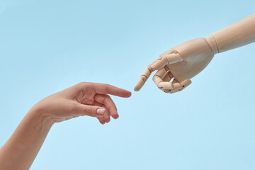 Woman and doll hands with almost touching fingers.