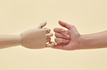 Two little fingers of mannequin and woman are together.