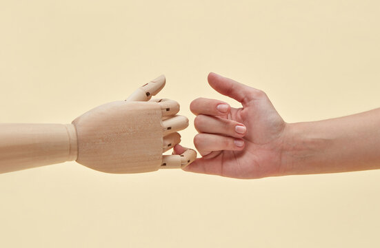 Two little fingers of mannequin and woman are together.
