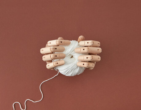 Artificial mannequin's hands hold the ball of thread.