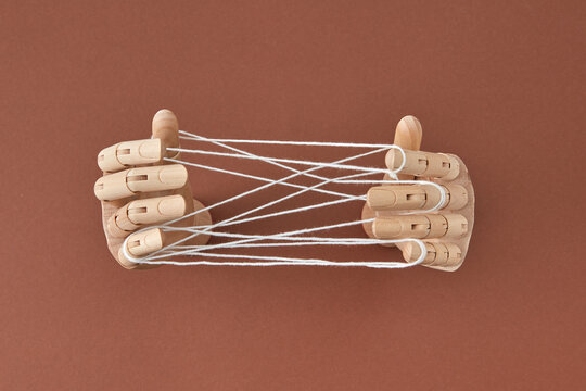 Top view wooden doll's hands play a Cat's cradle game.
