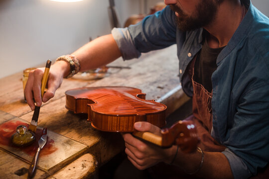 Anonymous luthier varnishing a violin