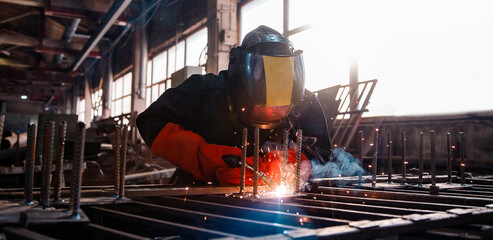 Welder in protective uniform with mask. Banner Factory industrial worker on workplace with spark