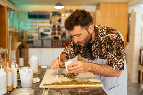 Focused man applying resin on board in studio