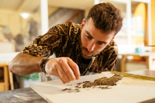 Focused craftsman creating miniature beach in art studio