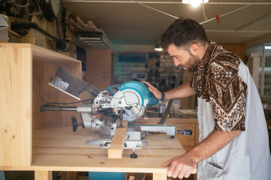 Focused joiner cutting wood with miter saw in workshop