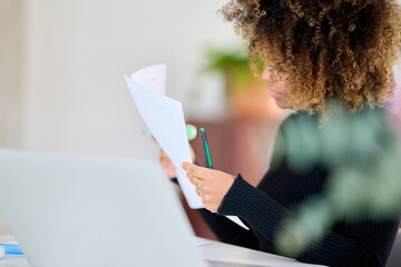 Businesswoman reading documents at desk.