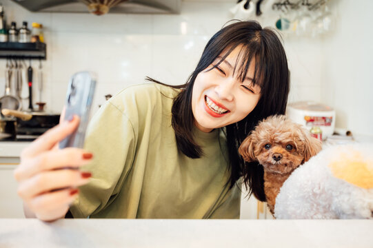 Young woman using smartphone with her pet dogs