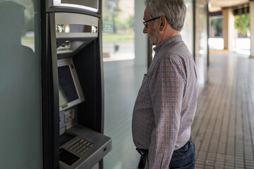 senior man at an ATM withdrawing cash