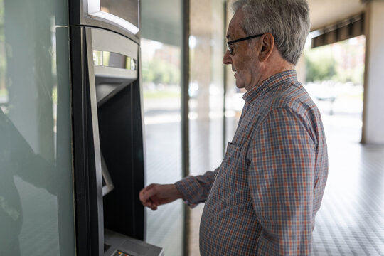 senior man at an ATM withdrawing cash