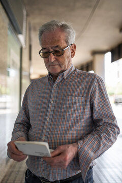 senior man looking at his bank account balance on the street