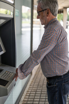 senior man at an ATM withdrawing cash