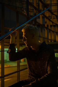 Lonely And Depressed Blonde Man Sitting On A Stair At Night.
