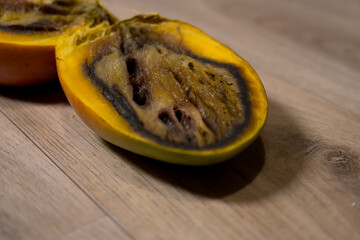 Close-up of a completely rotten cut mango on a wooden background.
