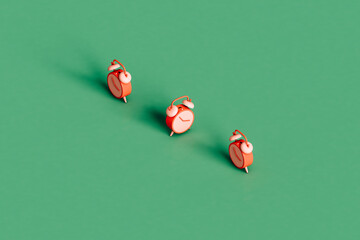 three pink alarm cloks on a green background. 3d render