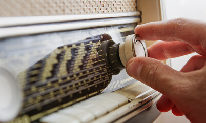 Close up of man hands adjusting frequency on vintage radio with knob