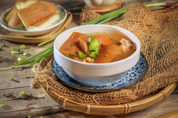 asian Chinese traditional herbal double boiled chicken pork meat hot soup with vegetables in bamboo bowl on retro kitchen dining background healthy menu