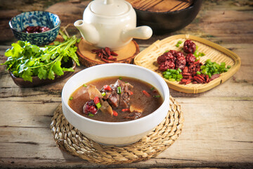 asian Chinese traditional herbal double boiled chicken pork meat hot soup with vegetables in bamboo bowl on retro kitchen dining background healthy menu