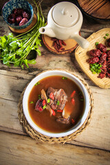 asian Chinese traditional herbal double boiled chicken pork meat hot soup with vegetables in bamboo bowl on retro kitchen dining background healthy menu