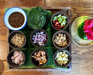Miang kham, Thai snack set which Leaf-Wrapped Bite-Size Appetizer of Wild Betel Leaf bush leave with ingredients chopped or cut into small pieces and a sweet and salty dressing sauce