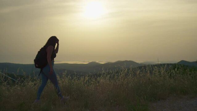 Slow motion video of a girl walking on a mountain slope at sunset. Hiking in the mountains with a backpack, a beautiful journey in the landscape of mountain peaks.