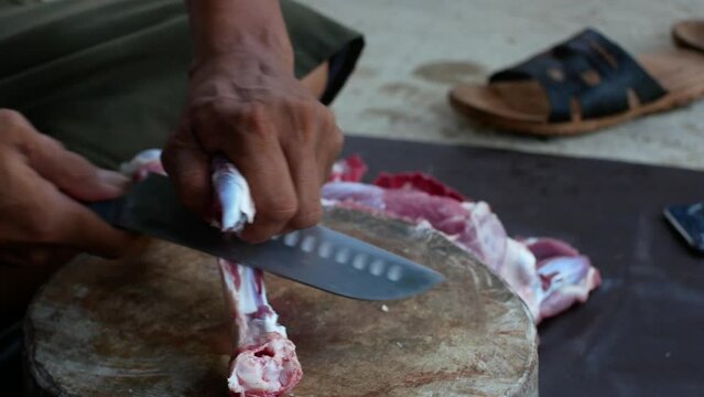 A local butcher in Indonesia cutting goat meat on a wooden cutting board