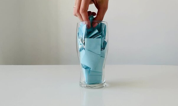 The hand takes one sticker from the glass and unfolds it