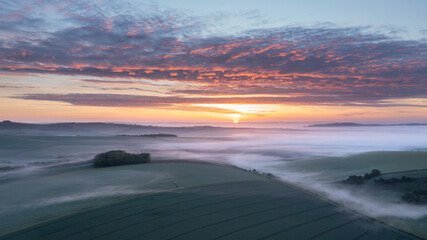 Fototapeta na wymiar Majestic drone landscape image of sea of fog rolling across South Downs English countryside during Spring sunrise