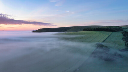 Majestic drone landscape image of sea of fog rolling across South Downs English countryside during Spring sunrise