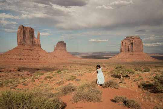 girl in blue dress at sunset in dessert of monument valley, Navajo tribal national park, arizona, usa