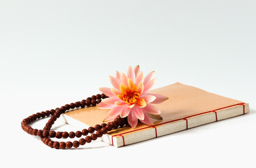 The Buddhist rosary, the Buddhist book and pink lotus flower